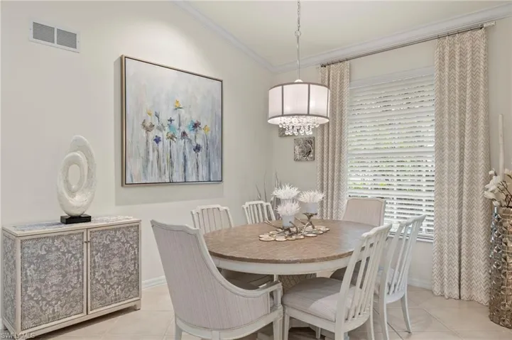 Dining area featuring light tile patterned flooring, lofted ceiling, and ornamental molding