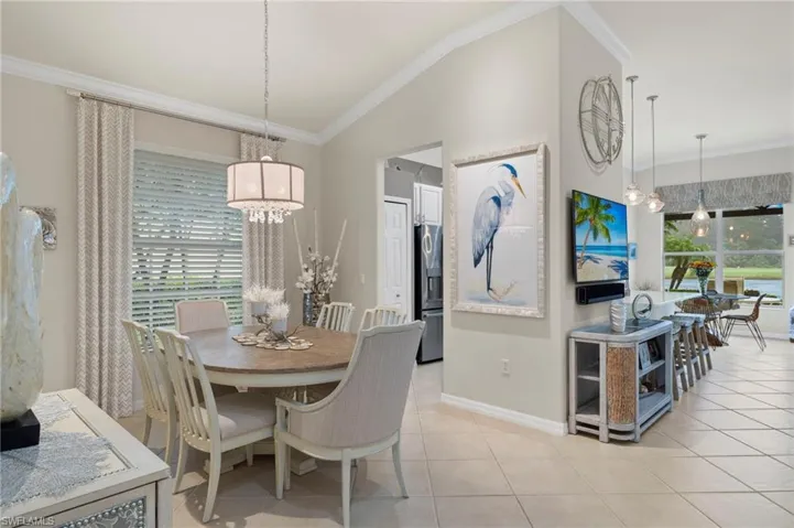 Tiled dining room featuring ornamental molding, a chandelier, and vaulted ceiling