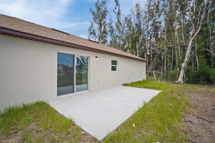 Back of house with a patio area, stucco siding, and roof with shingles