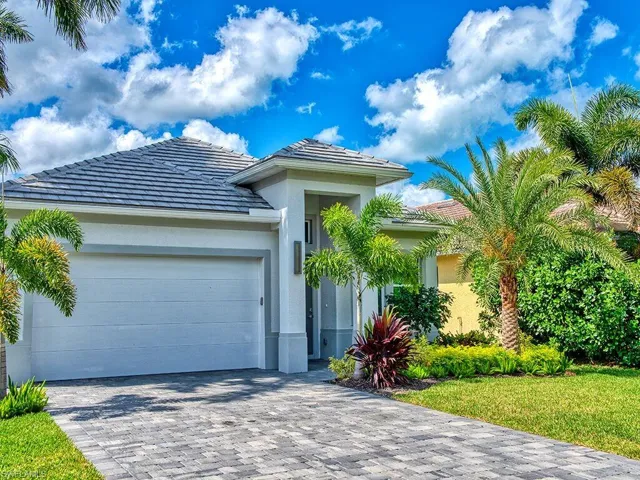 View of front of property featuring stucco siding, a tiled roof, decorative driveway, an attached garage, and a front yard