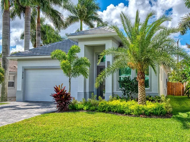 View of front facade with stucco siding, decorative driveway, and a garage