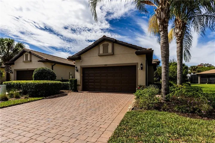 Ranch-style house with decorative driveway, a tiled roof, an attached garage, and stucco siding