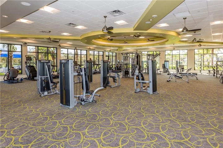 Exercise room featuring a tray ceiling, visible vents, and a ceiling fan