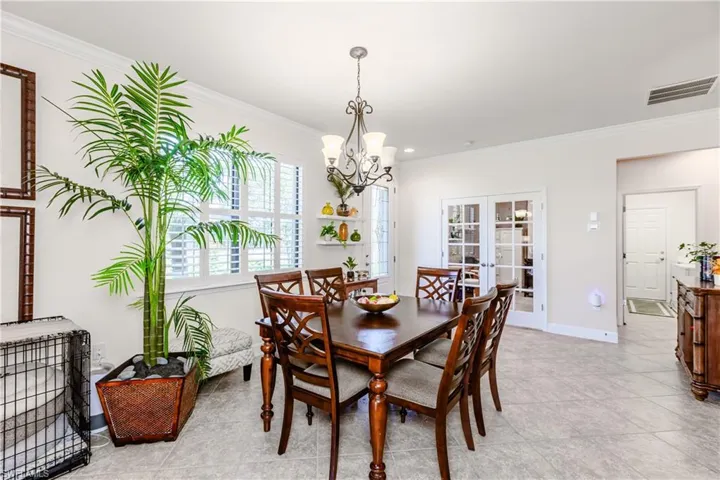 Dining space featuring a chandelier, visible vents, baseboards, ornamental molding, and french doors