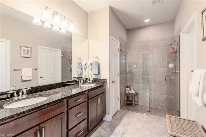 Bathroom featuring visible vents, a sink, a shower stall, and double vanity