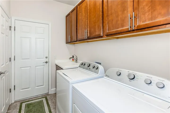 Laundry room featuring washing machine and dryer, a sink, and cabinet space