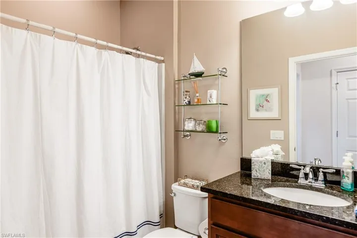 Bathroom with curtained shower, vanity, and toilet