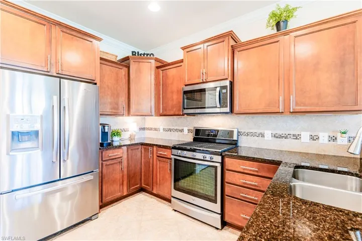 Kitchen with appliances with stainless steel finishes, crown molding, a sink, and tasteful backsplash