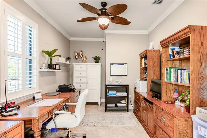 Office with light tile patterned floors, baseboards, visible vents, ceiling fan, and crown molding