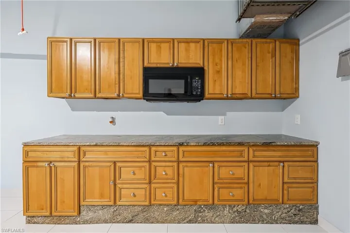 Wood-finish cabinetry with extensive storage, integrated microwave, and stone countertops