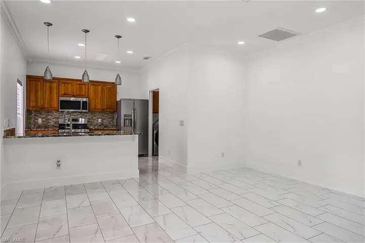 Open-concept living area with large format tile flooring, recessed lighting, and crown molding