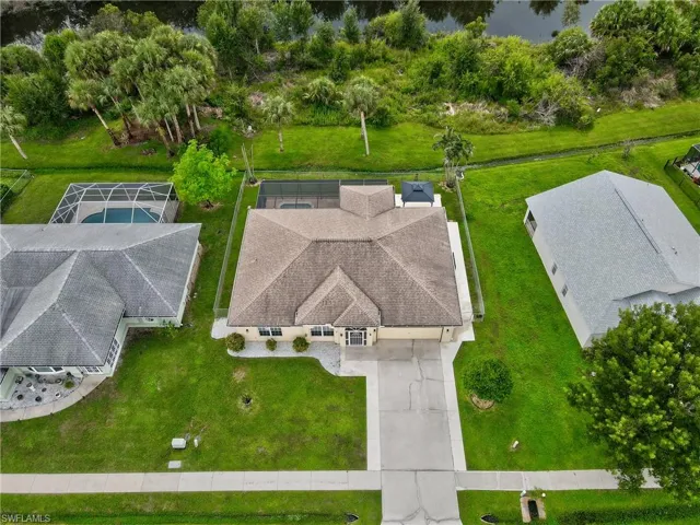Hip roof architecture with a screened pool enclosure, paved driveway, and mature landscaping