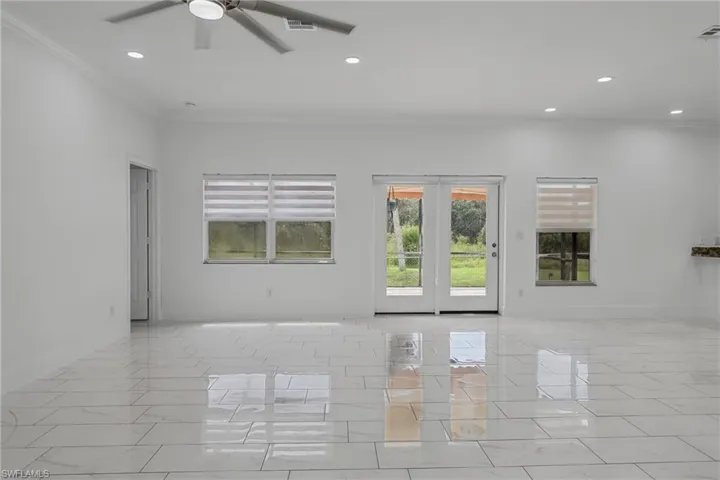 Polished tile flooring, recessed ceiling lighting, ceiling fan, and double French doors