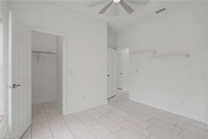 White tile flooring, white walls, and a ceiling fan