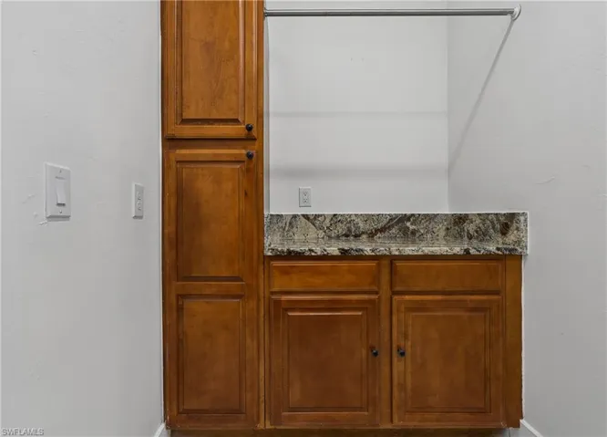 Built-in wood-finish cabinetry featuring multiple storage compartments and a stone-finish countertop