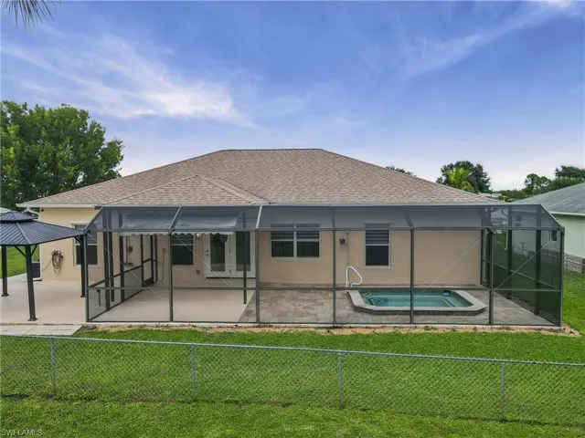Screened patio enclosure with an integrated spa, paved pool decking, and an additional paved patio area