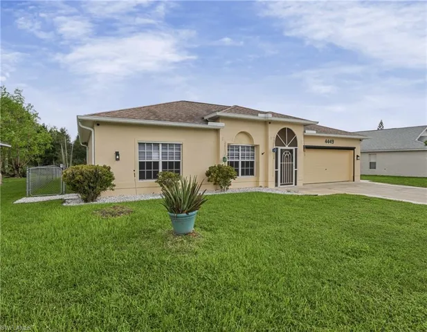 Stucco exterior with a tan finish, attached garage, arched entry, and a covered front porch