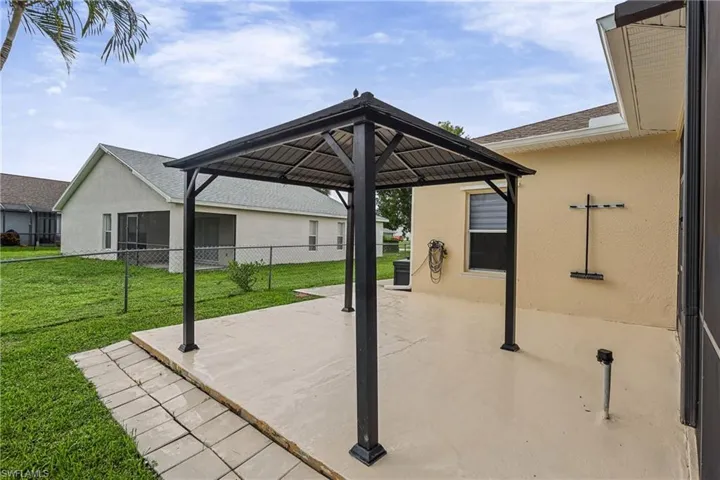 Paved patio with a black gazebo and exterior wall with textured stucco finish