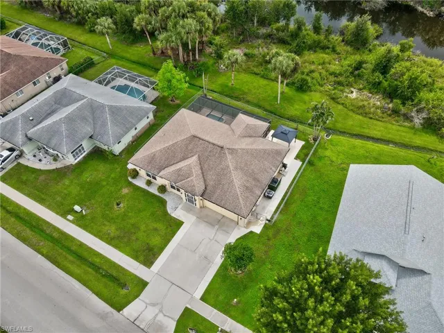Expansive property with a screened-in pool, long driveway, and concrete patio