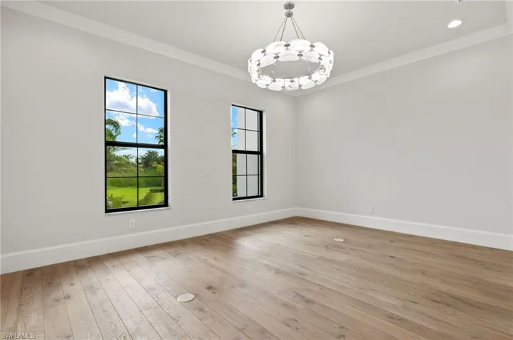 Spare room featuring crown molding, a notable chandelier, and light wood-type flooring