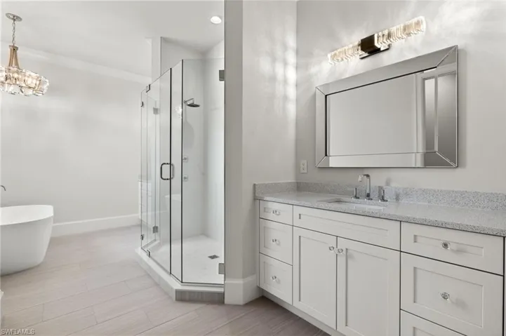 Bathroom with vanity, an inviting chandelier, and separate shower and tub