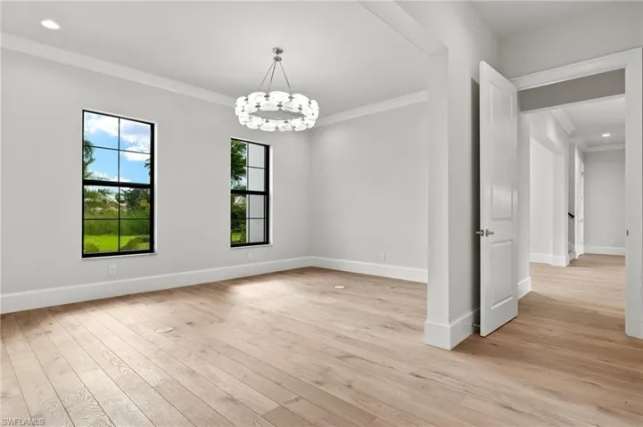 Unfurnished room with ornamental molding, light hardwood / wood-style flooring, and an inviting chandelier