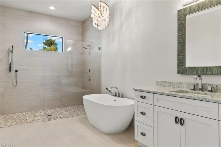 Bathroom featuring vanity, shower with separate bathtub, and an inviting chandelier