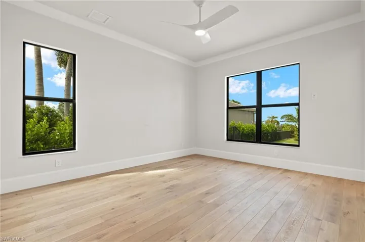 Spare room with a healthy amount of sunlight, light hardwood / wood-style floors, crown molding, and ceiling fan