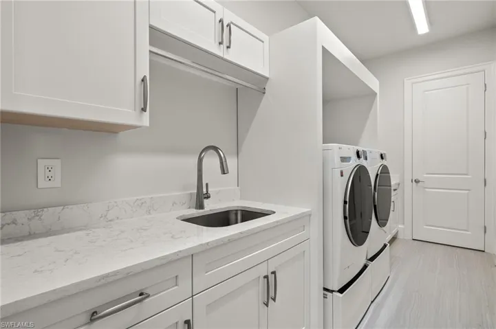 Clothes washing area featuring cabinets, sink, and washer and clothes dryer