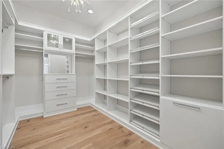 Spacious closet featuring an inviting chandelier and light wood-type flooring
