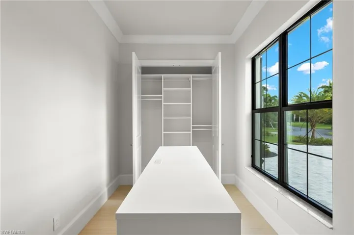 Walk in closet with light hardwood / wood-style flooring
