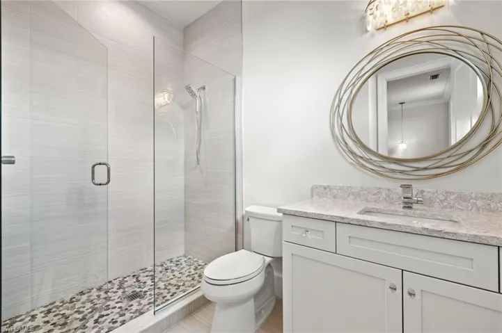 Bathroom with toilet, walk in shower, and vanity