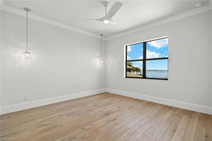 Empty room featuring a water view, crown molding, light hardwood / wood-style flooring, and ceiling fan