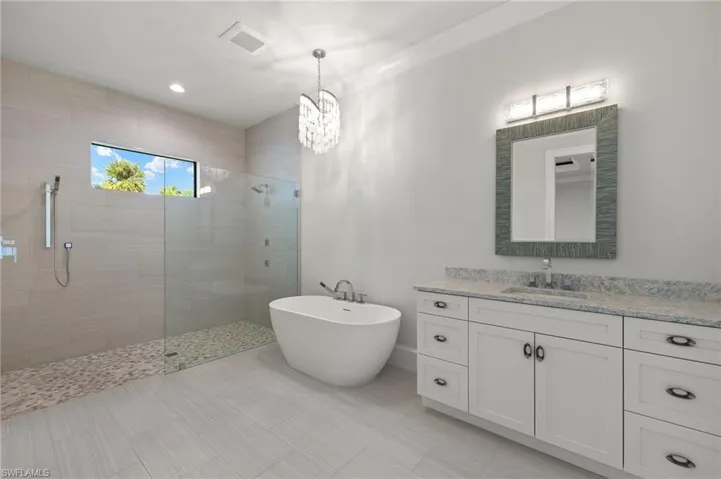Bathroom with vanity, an inviting chandelier, and plus walk in shower