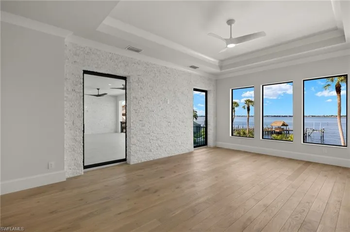 Spare room featuring a water view, ceiling fan, a raised ceiling, and light wood-type flooring