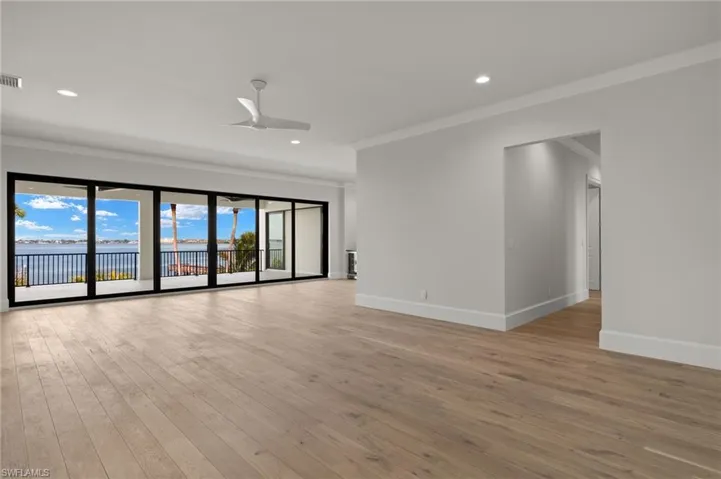 Unfurnished room with a water view, light hardwood / wood-style floors, ornamental molding, and ceiling fan