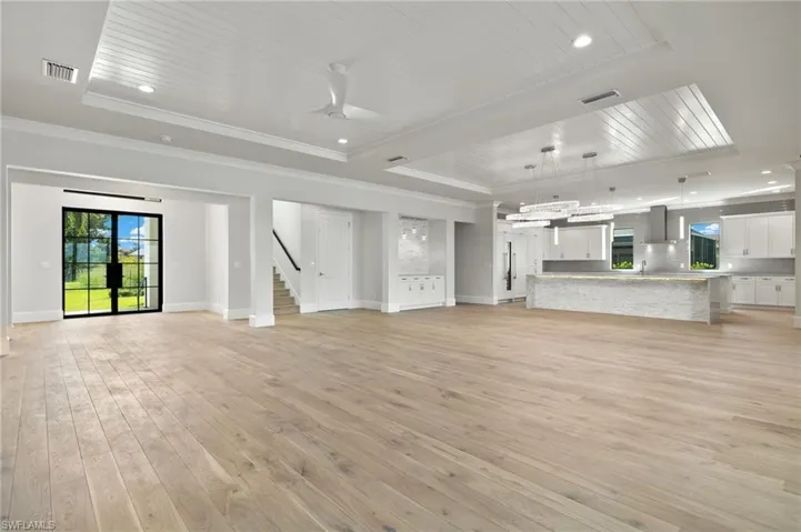 Unfurnished living room with ornamental molding, light hardwood / wood-style flooring, a tray ceiling, and ceiling fan