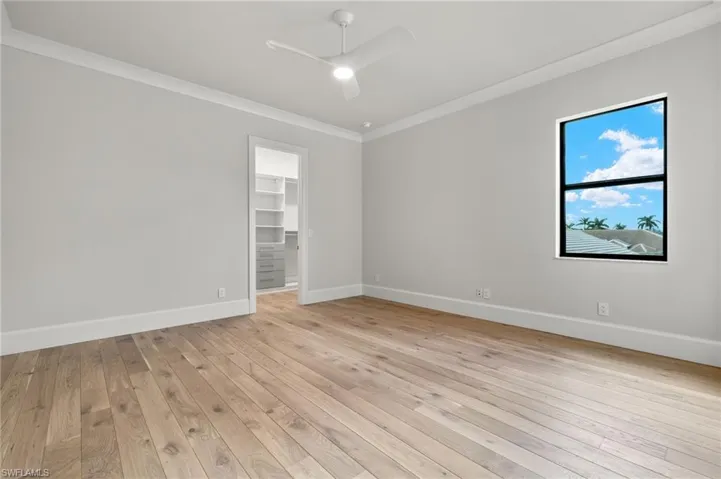 Empty room with light hardwood / wood-style floors, crown molding, and ceiling fan