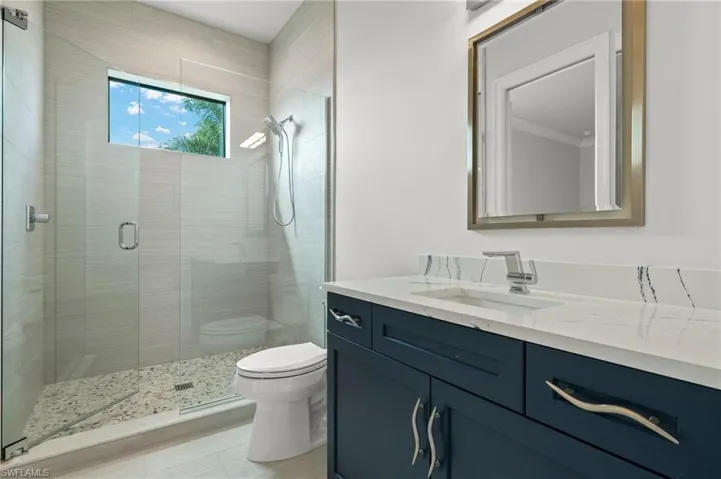 Bathroom featuring toilet, a shower with shower door, and vanity