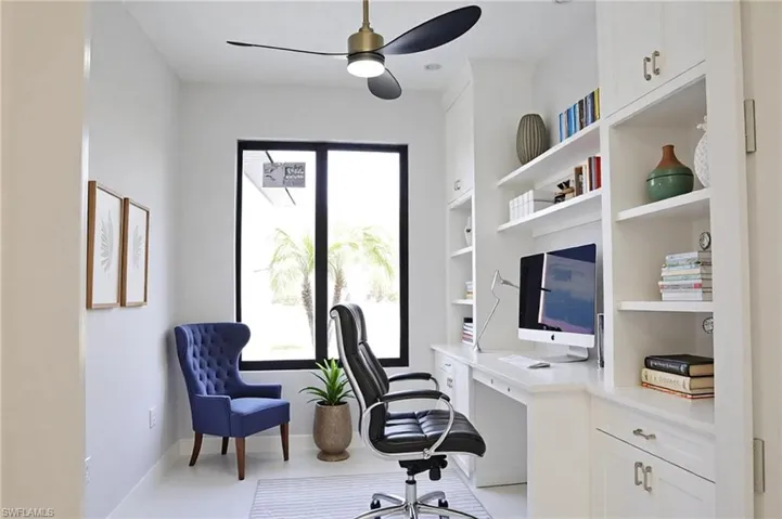 Office area with baseboards, a ceiling fan, built in shelves, and built in desk