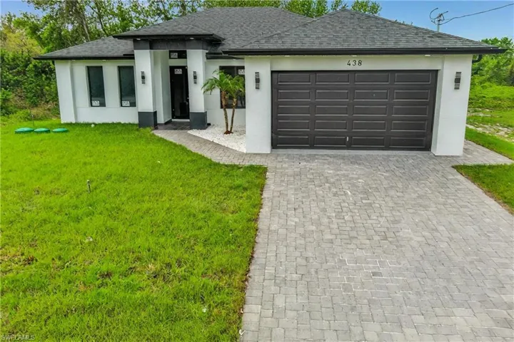 Prairie-style home featuring stucco siding, decorative driveway, a garage, and a front yard
