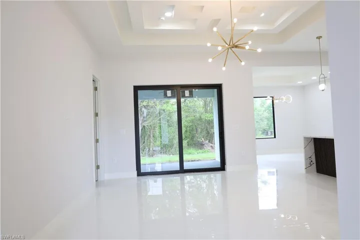 Unfurnished room with a chandelier, coffered ceiling, and baseboards