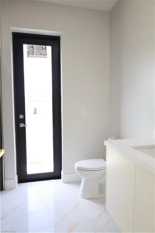Half bath with toilet, marble finish floor, and vanity
