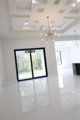 Empty room featuring beamed ceiling, baseboards, coffered ceiling, and a chandelier