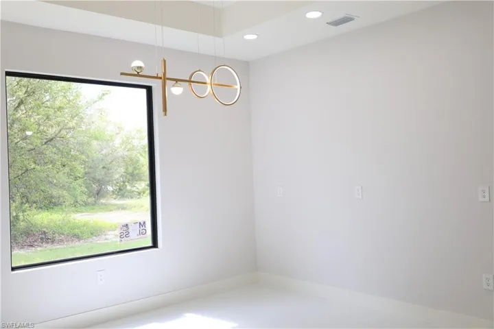Empty room with recessed lighting, visible vents, and a notable chandelier