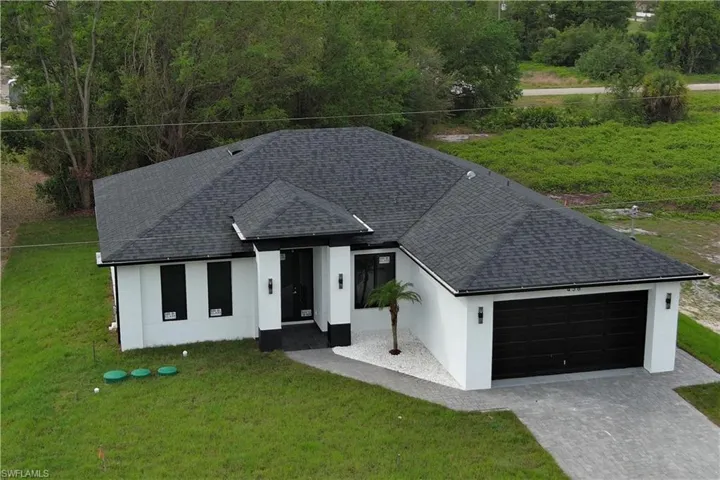 Ranch-style house with a front yard, decorative driveway, a garage, and a shingled roof