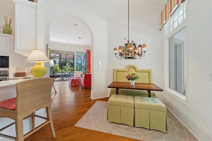 Dining area featuring arched walkways, a notable chandelier, crown molding, wood finished floors, and baseboards