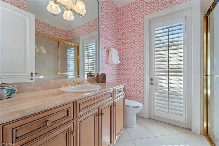 Full bath with vanity, a shower stall, toilet, and wallpapered walls