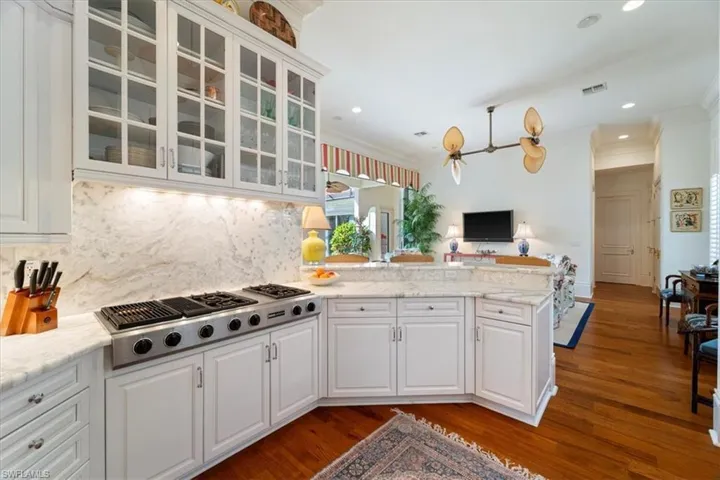 Kitchen featuring stainless steel gas cooktop, a peninsula, white cabinetry, and crown molding