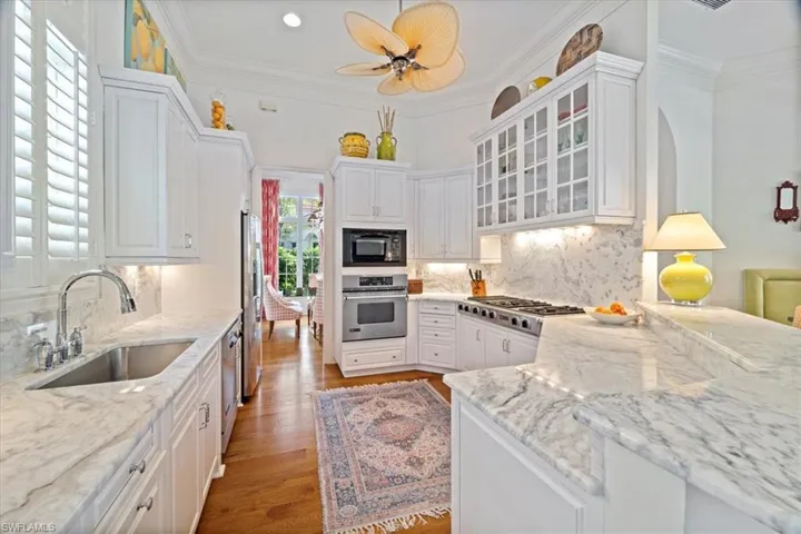 Kitchen with appliances with stainless steel finishes, white cabinetry, a sink, and ornamental molding